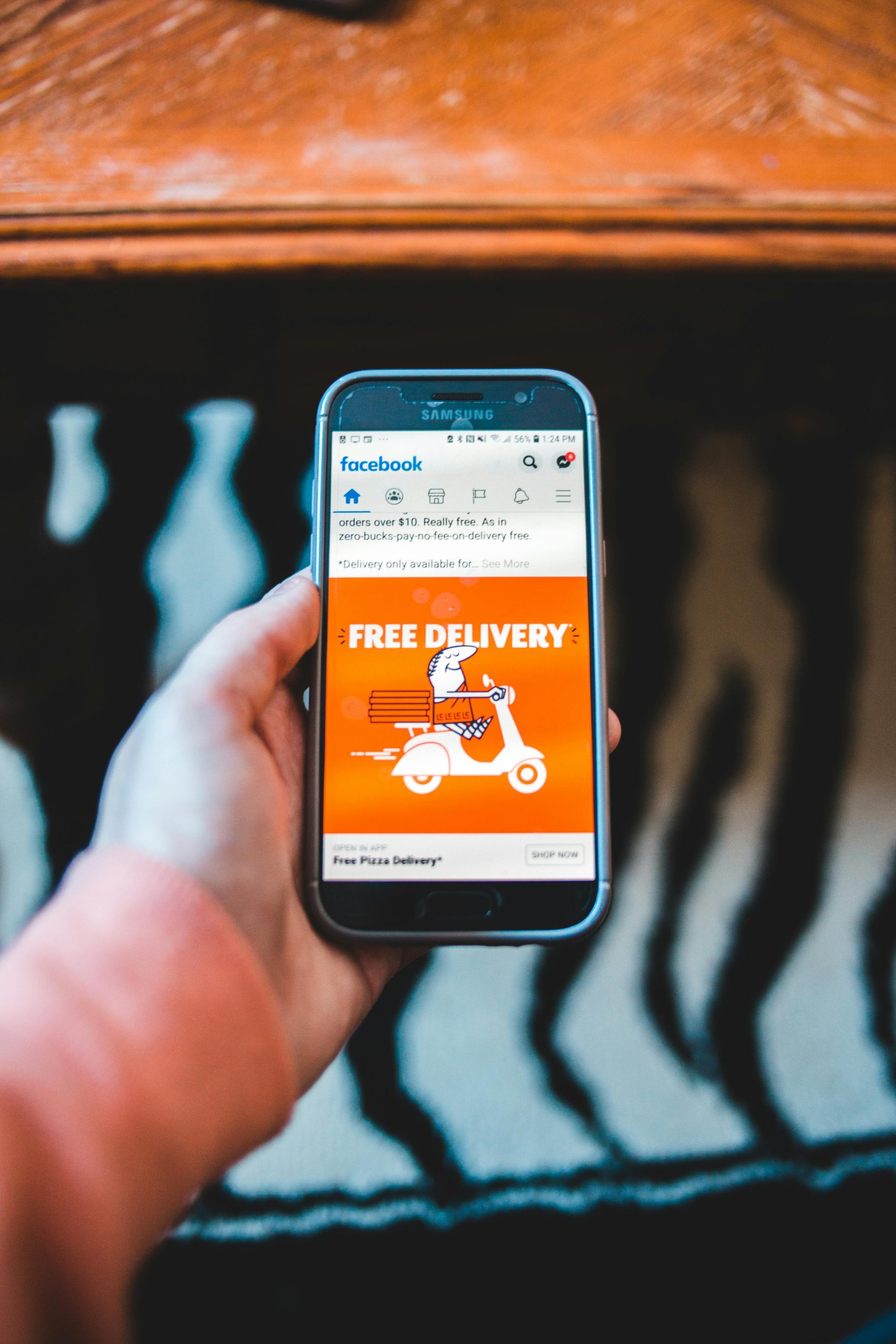 Hand holding a phone displaying a "Free Delivery" social media ad, an example of storytelling that moves people closer
