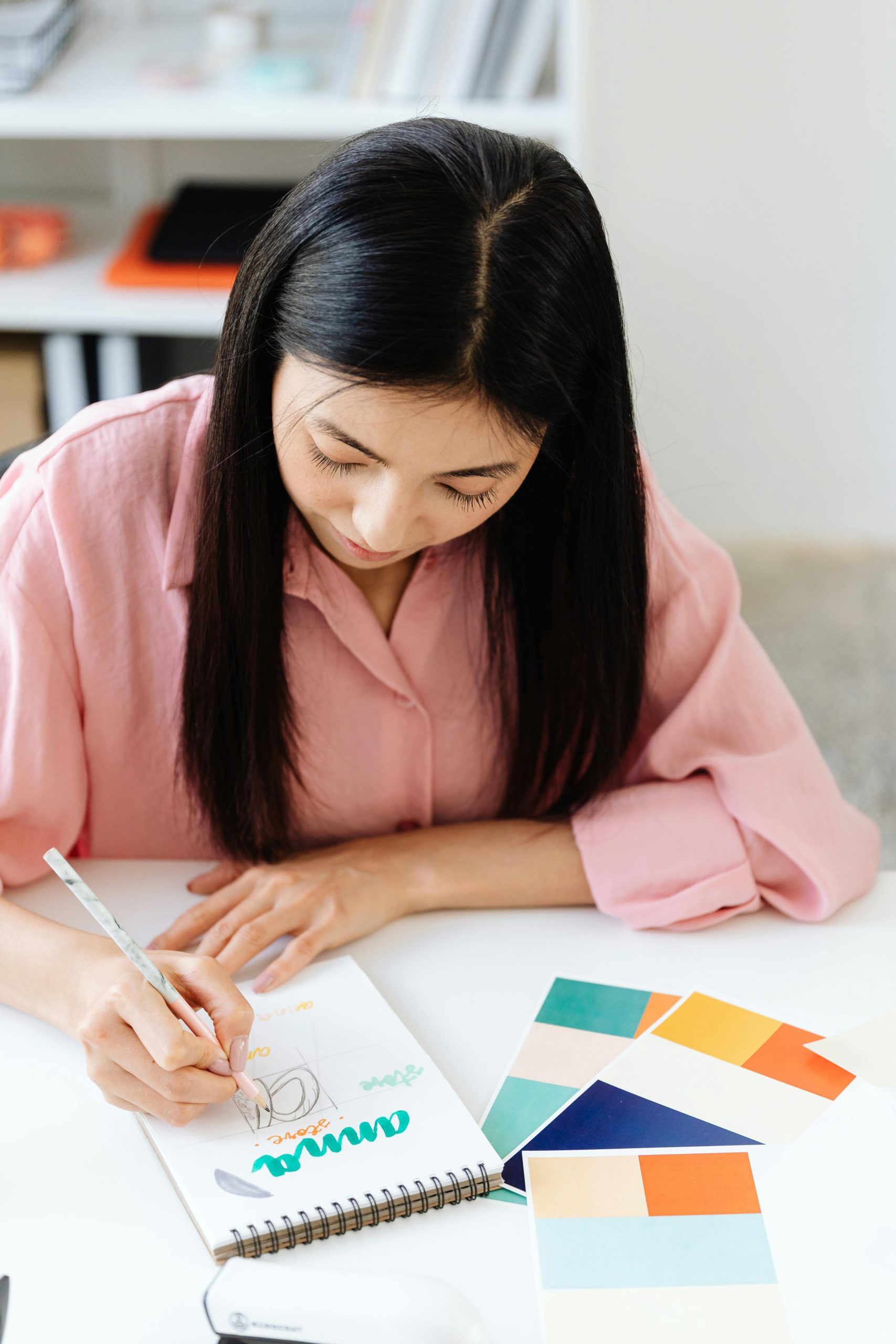 Designer sketching brand lettering beside a fanned-out color palette, building a clear, credible brand