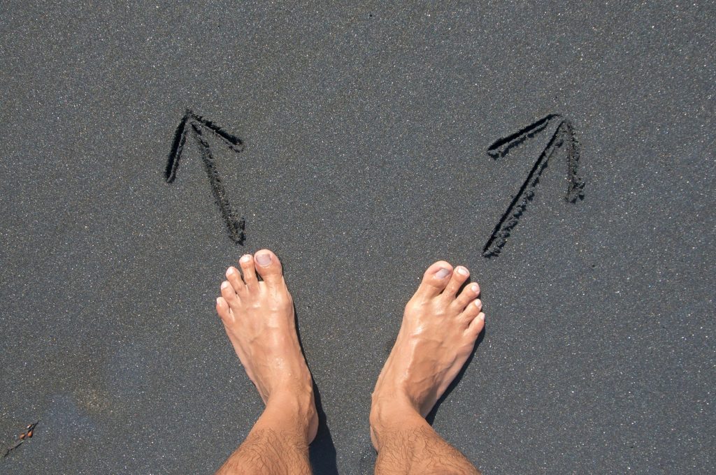 Bare feet standing on pavement between two arrows pointing opposite ways, the moment of faster, clearer decision-making