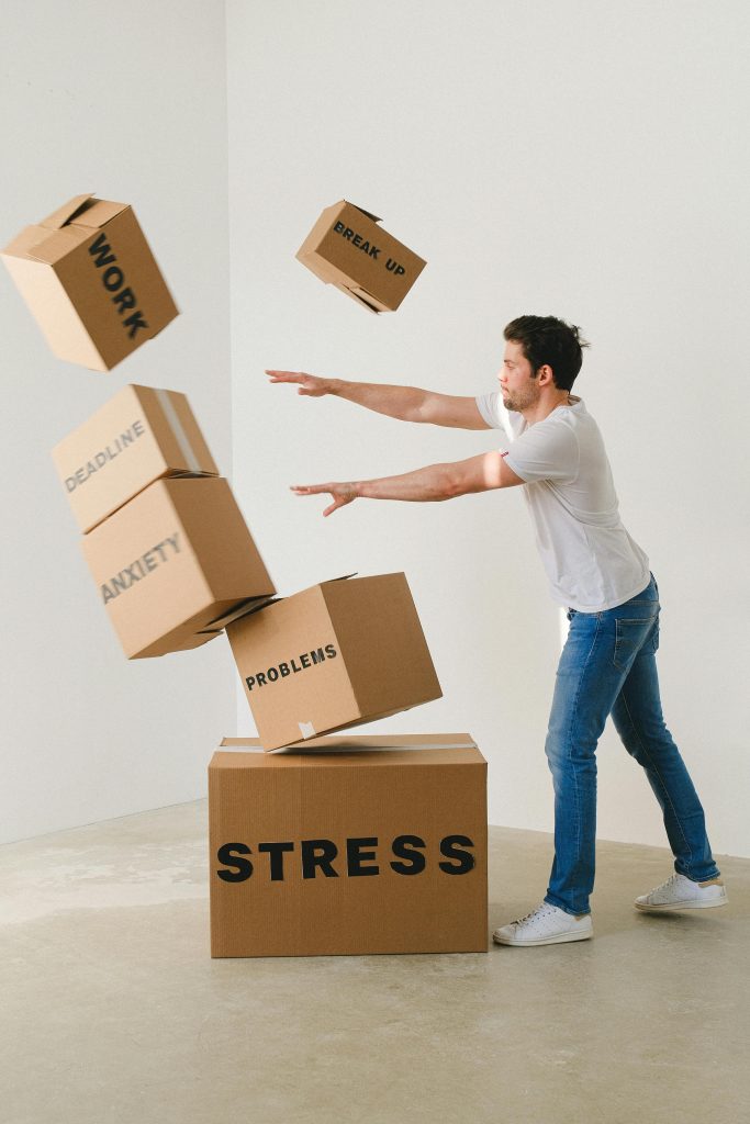 A person carrying stacked cardboard boxes labeled "Anxiety" and "Problems," the load you keep moving through until the pattern is interrupted